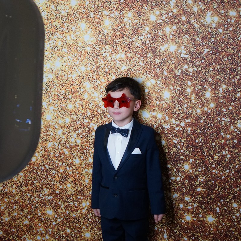 Guest in suit posing at gold glitter backdrop